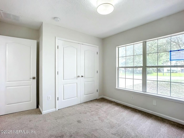 unfurnished bedroom featuring light colored carpet and a closet