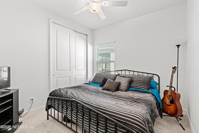 bedroom featuring light colored carpet, ceiling fan, and a closet