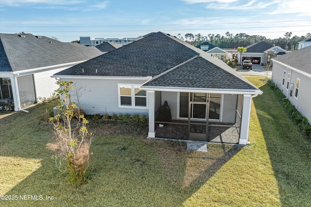 rear view of house featuring a lawn and a sunroom