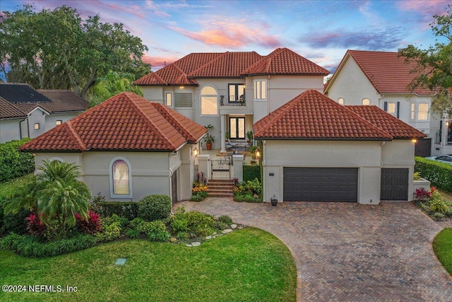 mediterranean / spanish home featuring a yard, a garage, and a balcony