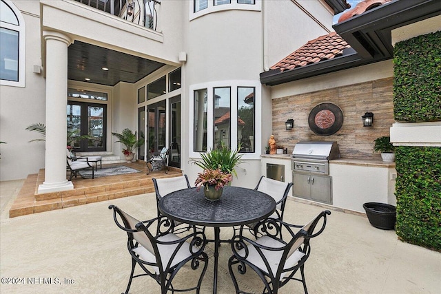 view of patio with french doors, a balcony, a grill, and exterior kitchen