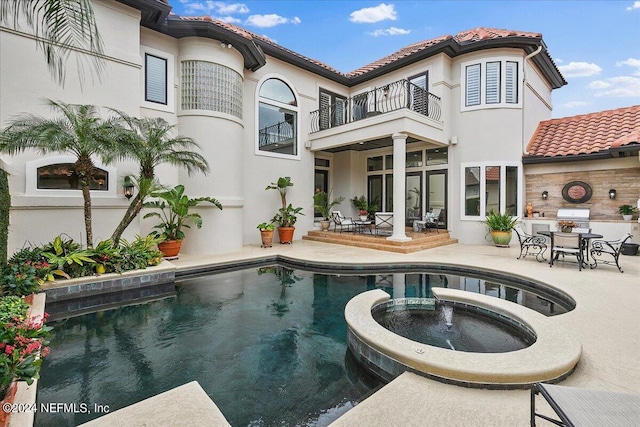 back of property with a patio, a balcony, and an in ground hot tub