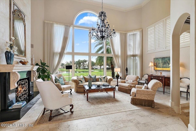 interior space with a towering ceiling, ornamental molding, a fireplace, and a chandelier