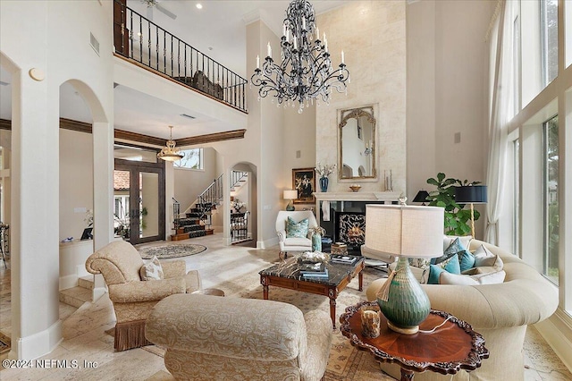 living room featuring a high ceiling, a premium fireplace, and an inviting chandelier