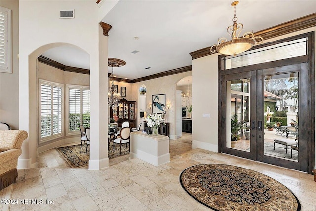 foyer entrance featuring crown molding, an inviting chandelier, and french doors