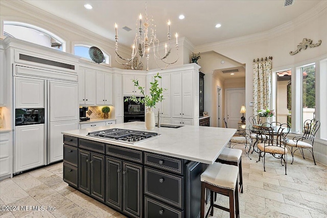 kitchen with sink, a center island with sink, paneled built in refrigerator, stainless steel gas stovetop, and white cabinets