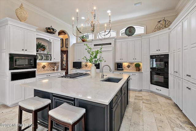 kitchen with built in microwave, sink, an island with sink, and white cabinets