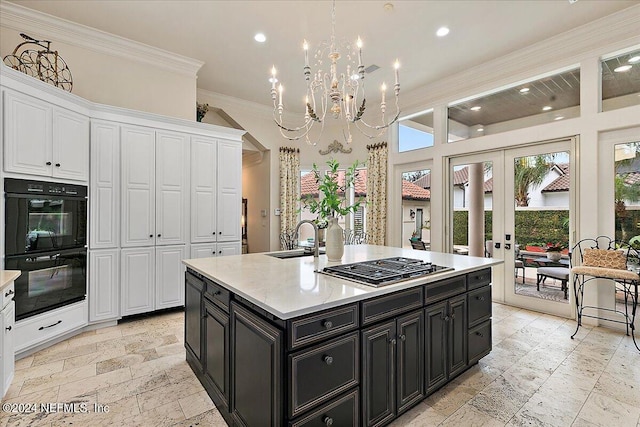 kitchen featuring sink, crown molding, double oven, an island with sink, and white cabinets