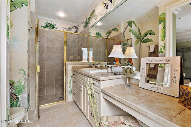 bathroom featuring crown molding, toilet, vanity, and a shower with shower door