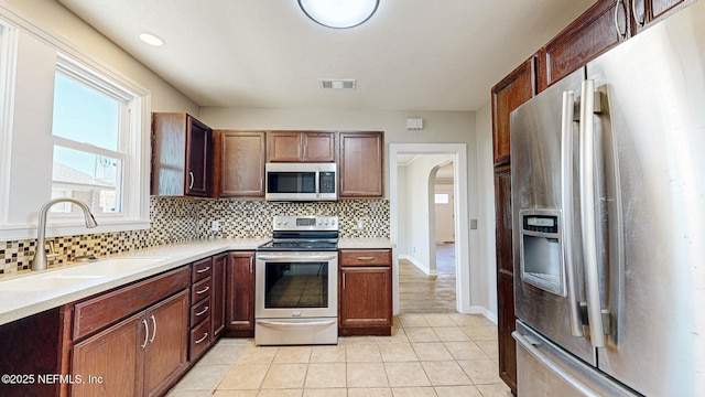 kitchen with tasteful backsplash, appliances with stainless steel finishes, sink, and light tile patterned floors