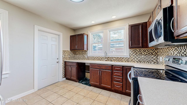 kitchen with light tile patterned flooring, appliances with stainless steel finishes, sink, and decorative backsplash