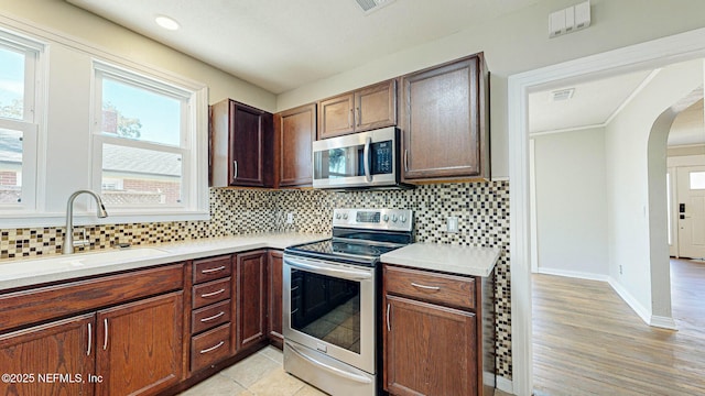 kitchen featuring tasteful backsplash, a healthy amount of sunlight, stainless steel appliances, and sink