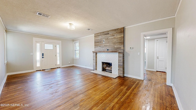 unfurnished living room featuring hardwood / wood-style flooring, ornamental molding, a large fireplace, and a textured ceiling