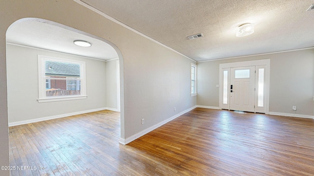 entryway with crown molding, hardwood / wood-style floors, and a textured ceiling