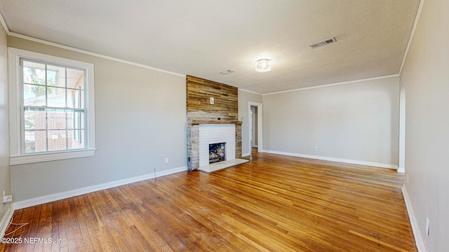 unfurnished living room featuring hardwood / wood-style flooring, crown molding, and a brick fireplace