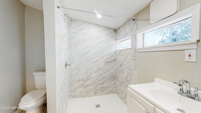 bathroom featuring tiled shower, vanity, and toilet