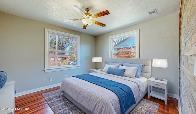 bedroom featuring ceiling fan, dark hardwood / wood-style floors, and a textured ceiling