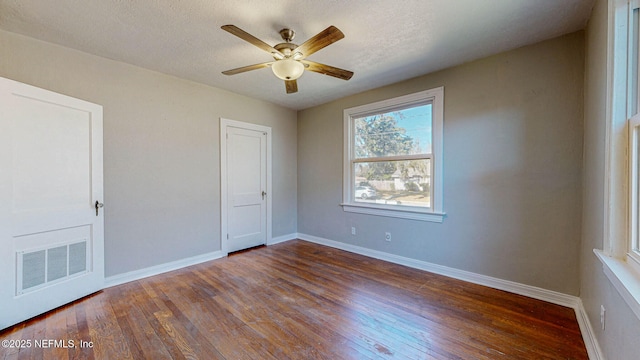 unfurnished bedroom with a textured ceiling, dark hardwood / wood-style floors, and ceiling fan