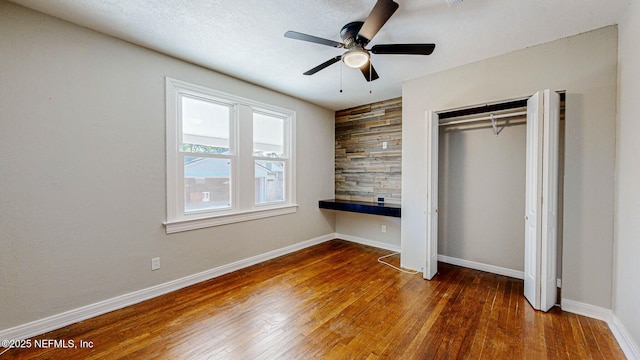 unfurnished bedroom featuring dark wood-type flooring, ceiling fan, and a closet