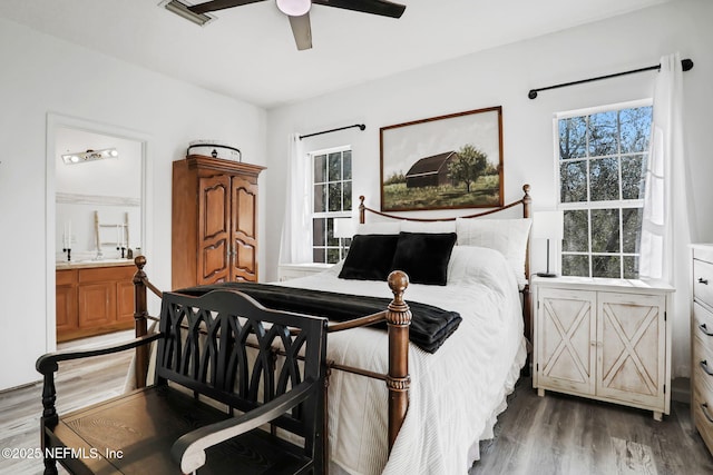 bedroom with ceiling fan, ensuite bath, and dark hardwood / wood-style floors