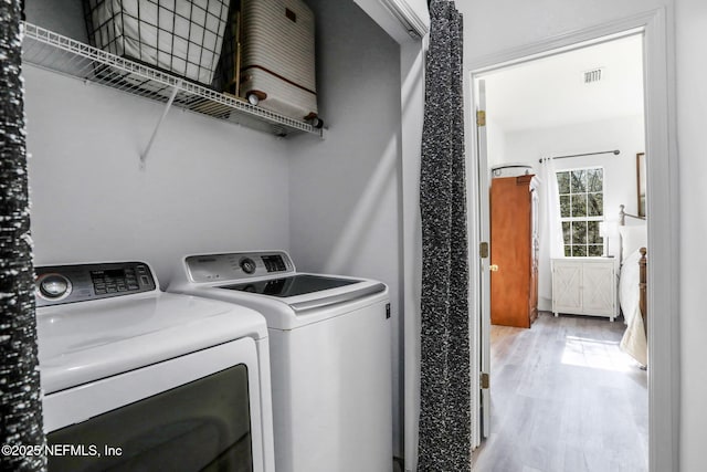 laundry area with washing machine and dryer and light wood-type flooring