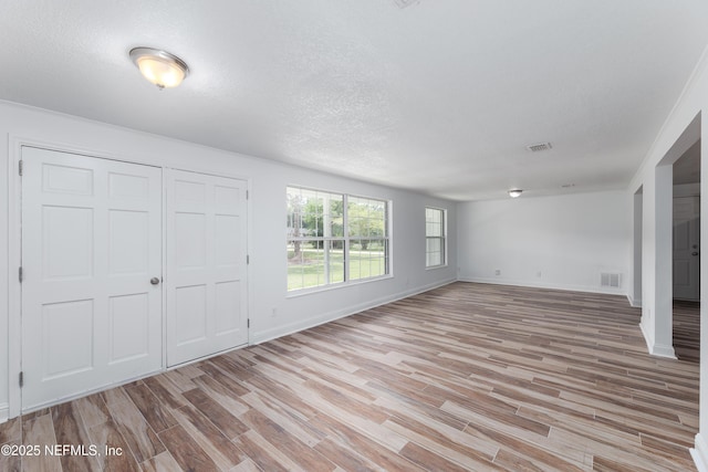 unfurnished bedroom featuring a closet, a textured ceiling, and light wood-type flooring