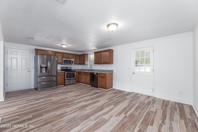 kitchen featuring appliances with stainless steel finishes, sink, light hardwood / wood-style flooring, and a textured ceiling