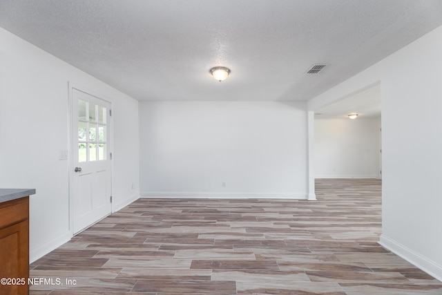 empty room featuring a textured ceiling and light hardwood / wood-style flooring