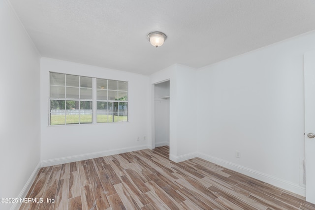 unfurnished room with ornamental molding, light hardwood / wood-style flooring, and a textured ceiling