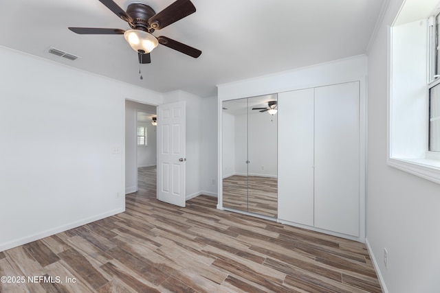 unfurnished bedroom featuring crown molding, a closet, ceiling fan, and light wood-type flooring