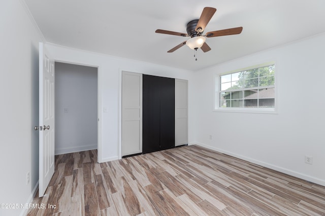 unfurnished bedroom featuring ornamental molding, a closet, ceiling fan, and light wood-type flooring