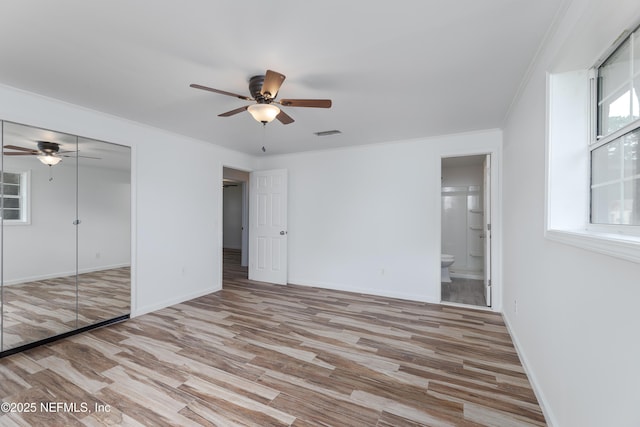 unfurnished bedroom with ensuite bath, ornamental molding, ceiling fan, and light wood-type flooring