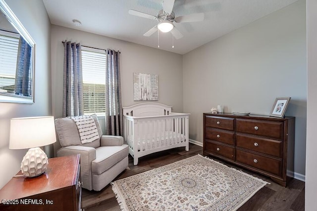 bedroom featuring dark hardwood / wood-style flooring, a nursery area, and ceiling fan