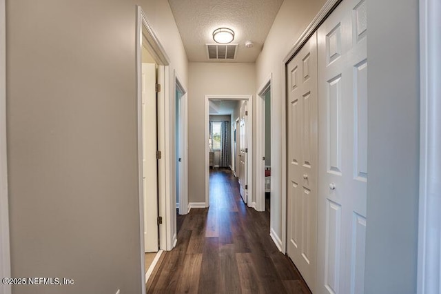 hallway featuring dark hardwood / wood-style flooring and a textured ceiling