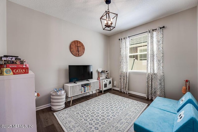 living room featuring dark hardwood / wood-style flooring, a textured ceiling, and an inviting chandelier