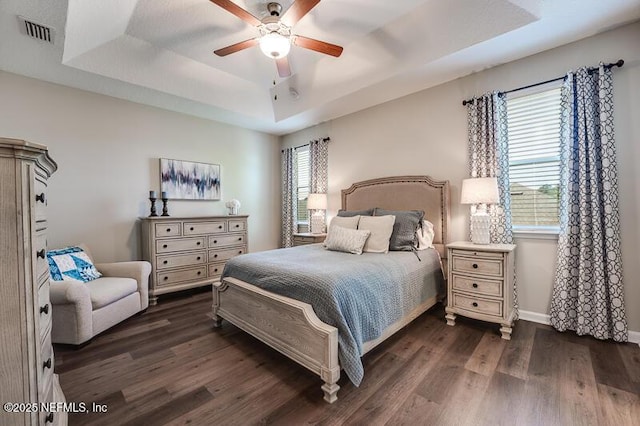 bedroom featuring ceiling fan, dark hardwood / wood-style floors, and a raised ceiling