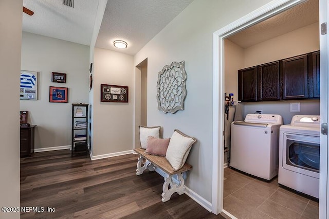 clothes washing area with cabinets, hardwood / wood-style floors, washing machine and clothes dryer, and a textured ceiling