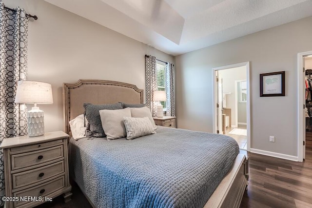 bedroom with dark wood-type flooring, ensuite bathroom, and a spacious closet