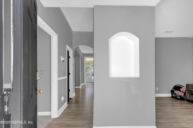 corridor with a textured ceiling and light wood-type flooring