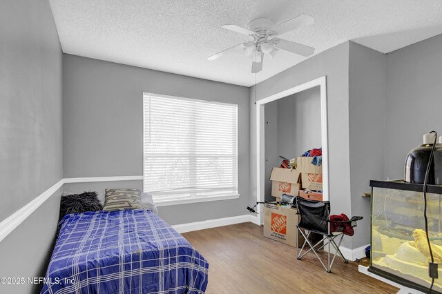 bedroom with ceiling fan, hardwood / wood-style floors, and a textured ceiling