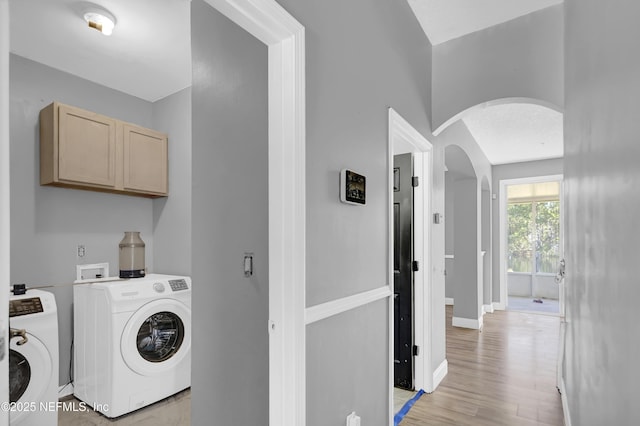 laundry area with cabinets, washer and dryer, and light hardwood / wood-style flooring