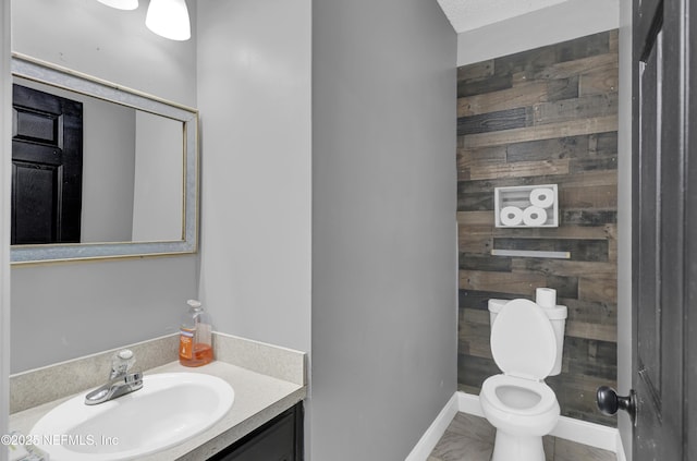 bathroom with vanity, toilet, and wood walls