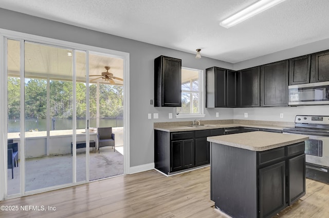 kitchen featuring a kitchen island, sink, stainless steel appliances, a textured ceiling, and light hardwood / wood-style flooring