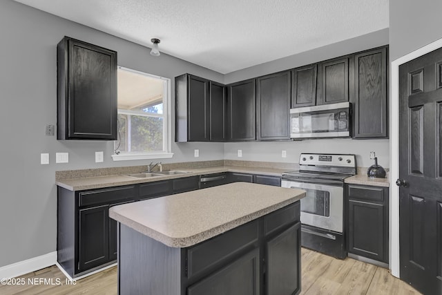 kitchen featuring sink, a textured ceiling, light wood-type flooring, a kitchen island, and stainless steel appliances