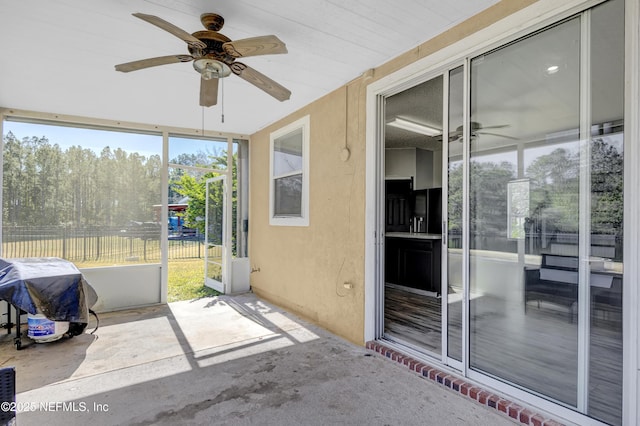 unfurnished sunroom featuring ceiling fan