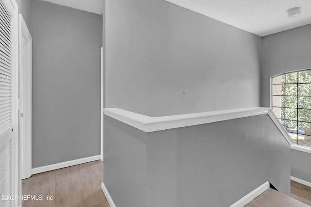 hall with wood-type flooring and a textured ceiling