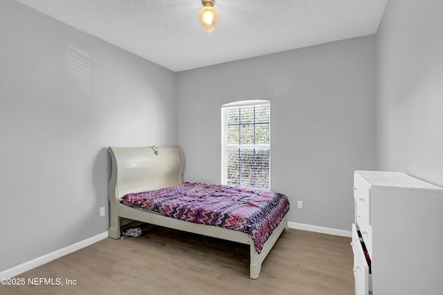 bedroom with light hardwood / wood-style flooring and a textured ceiling