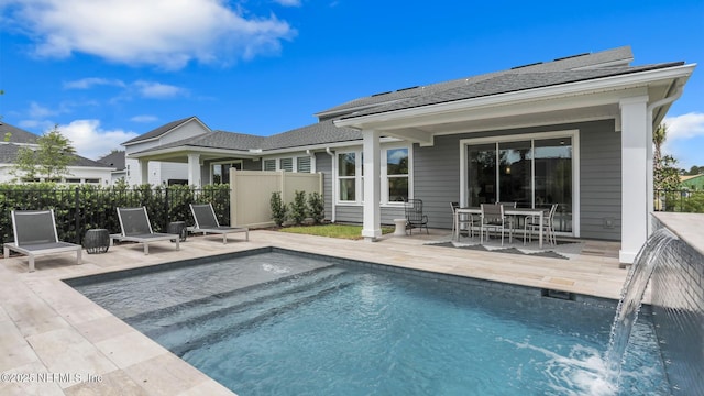 back of property featuring a fenced in pool, pool water feature, and a patio area