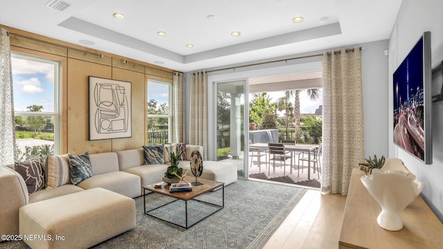 living room with a raised ceiling and hardwood / wood-style floors