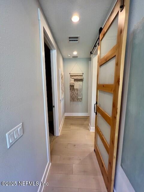 hallway featuring a barn door and light wood-type flooring